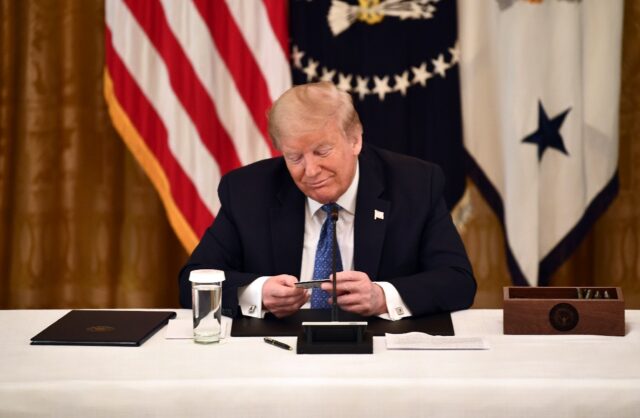 Former US president Donald Trump, holding a debit card during a 2020 cabinet meeting, has