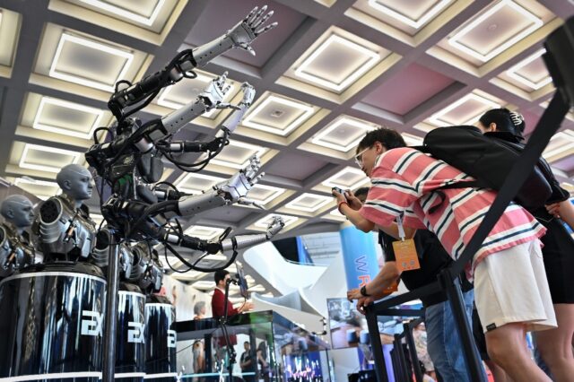 Visitors take pictures of robot arms at the 2023 World Robot Conference in Beijing on Augu