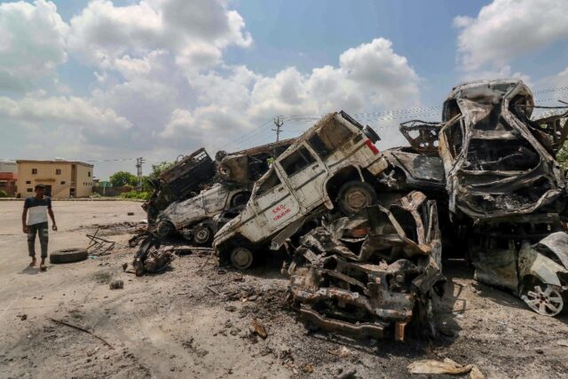 A man walks past burned vehicles after violent clashes in Nuh, near the Indian capital New