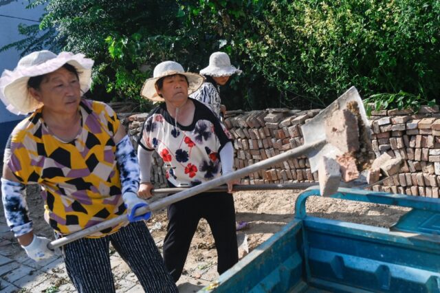 Women collect bricks strewn on the ground near the epicenter of the quake in Shandong’s