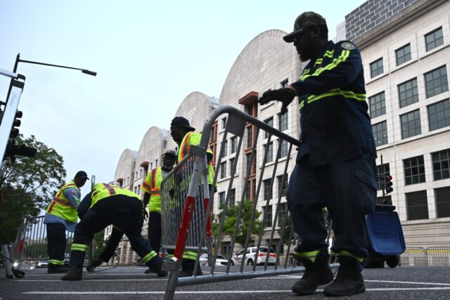 Workers set up barricades before the arrival of former US president Donald Trump for arrai