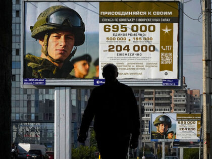 A man walks past advertising billboards which promote contract military service in the Rus