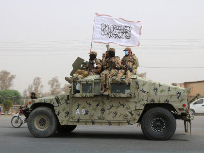 Taliban fighters patrol on the road during a celebration marking the second anniversary of