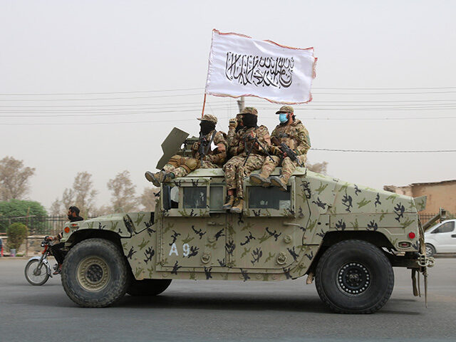 Taliban fighters patrol on the road during a celebration marking the second anniversary of