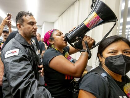 ORANGE, CA - SEPTEMBER 07: A security guard escorts a woman using a megaphone out of the b