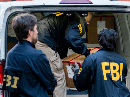 Federal agents load a vehicle with evidence boxes taken from a property related to Russian