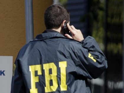 A federal agent talks on his phone after authorities from the FBI and Department of Energy
