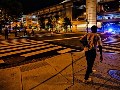 WASHINGTON, DC - JULY 17: A resident walks past the crime scene as the Washington Metropolitan Police Department conducts an investigation at the scene of a shooting outside the Third Base Gate of Nationals Park on July 17, 2021 in Washington, DC. At least two people were shot outside the …