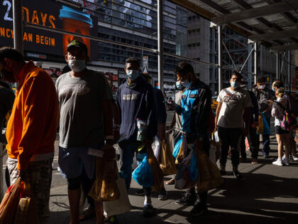 A group of migrants wait in line after arriving from Texas, outside Port Authority Bus Ter