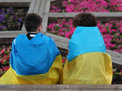 Children sit wrapped with the Ukrainian flag attend a gathering in the Israeli city of Tel Aviv, to mark Ukraine's Independence Day (from the Soviet Union in 1991) and the six-month anniversary of the Russian invasion of Ukraine, on August 24, 2022. (Photo by JACK GUEZ / AFP) (Photo by …