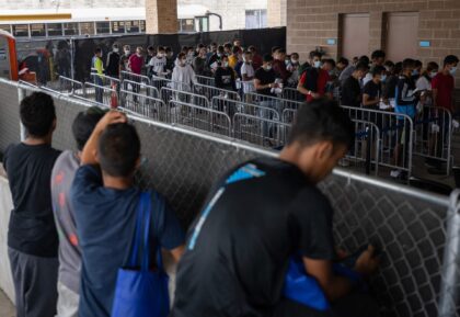 Migrants look over a fence as they try to locate family members and friends that arrived at a processing center in Brownsville, Texas, on May 11, 2023. The US on May 11, 2023, will officially end its 40-month Covid-19 emergency, also discarding the Title 42 law, a tool that has …