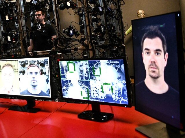 An employee stands in a cage, from which dozens of cameras simultaneously capture his imag