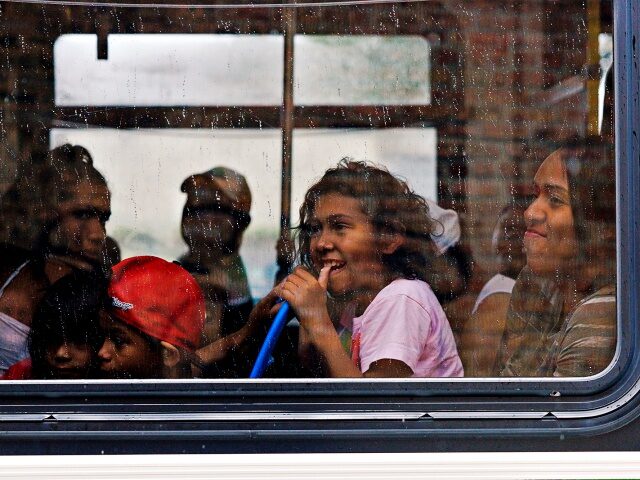 Migrants look out the window as they ride a CTA bus leaving the High Ridge YMCA shelter to
