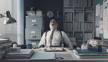 Lazy exhausted businessman sitting at office desk and sleeping, he is snoring with his mou