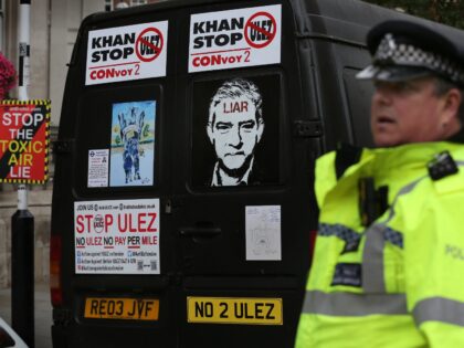 LONDON, UNITED KINGDOM - 2023/07/22: A police officer watches vehicles arriving with protest signs attached to their back doors outside the BBC. Protesters joined together to make it clear to London Mayor Sadiq Khan that he and the extension to the existing Ultra Low Emissions Zone (ULEZ) in London are …