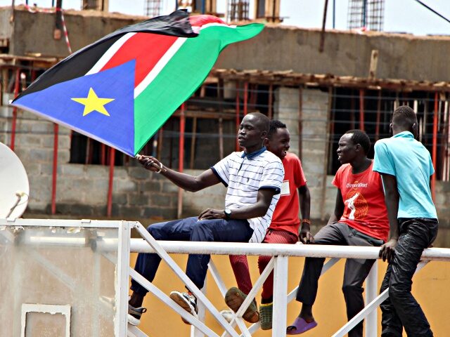 A South Sudanese basketball supporter waves a South Sudanese flag while watching a live br