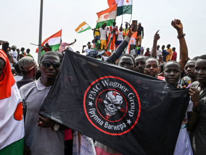 Men hold a flag bearing the logo of Private Military Company (PMC) Wagner as supporters of Niger's National Council of Safeguard of the Homeland (CNSP) protest outside the Niger and French airbase in Niamey on September 2, 2023 to demand the departure of the French army from Niger. (Photo by …