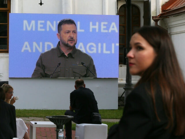 Ukrainians look on the screen as President of Ukraine Volodymyr Zelensky speaks during the