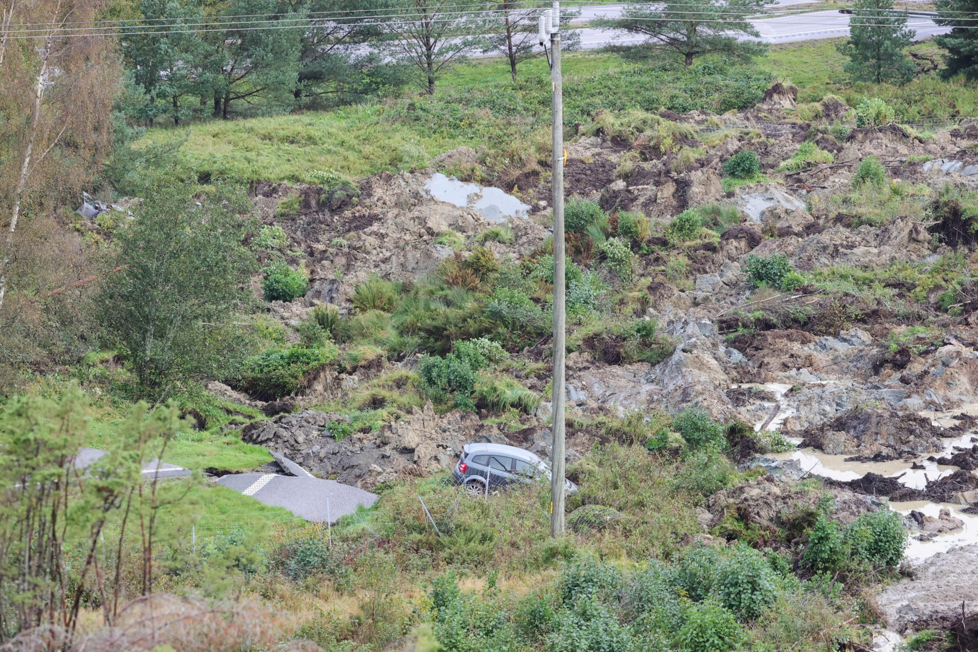 A car is seen in the debris of a street near Stenungsund, Sweden, on September 23, 2023. The E6 highway near Stenungsund was closed in both directions after persistent rain had caused a large landslide where several cars and a buses went down. Three people were said to be injured. (Photo by Adam IHSE / TT News Agency / AFP) / Sweden OUT (Photo by ADAM IHSE/TT News Agency/AFP via Getty Images)