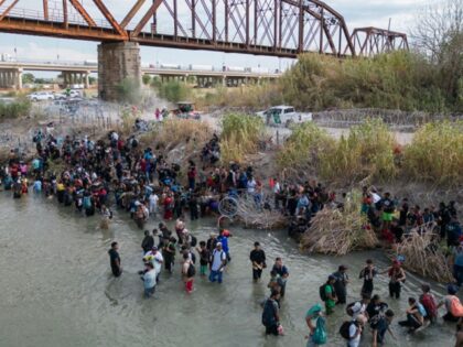 This aerial photo shows migrants waiting in the Rio Grand for an opening in the razor wire