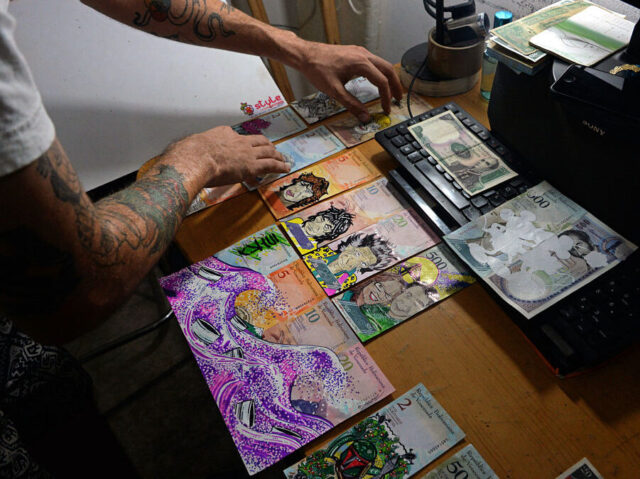 Venezuelan illustrator Jose Leon shows his artworks painted on devalued Bolivar bills, at his workshop in San Cristobal, Venezuela on February 2, 2018. Using devalued Bolivar bills as raw material, this Venezuelan young artist found the way to make a living, increasing the value of the currency up to 5000%, by selling his artworks to foreign customers. / AFP PHOTO / GEORGE CASTELLANOS / TO GO WITH AFP STORY by Margioni BERMUDEZ (Photo credit should read GEORGE CASTELLANOS/AFP via Getty Images)