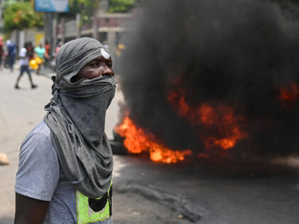 A man stands near a burning tire during a demonstration against insecurity in Carrefour-Fe