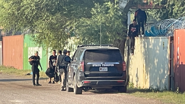 A Texas DPS trooper detains a group of migrants who scaled a Conex container wall in Eagle Pass, Texas. (Randy Clark/Breitbart Texas)