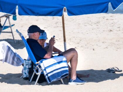 US President Joe Biden and First Lady Jill Biden sit under an umbrella at Rehoboth Beach, Delaware, on August 2, 2023. (Photo by Jim WATSON / AFP) (Photo by JIM WATSON/AFP via Getty Images)