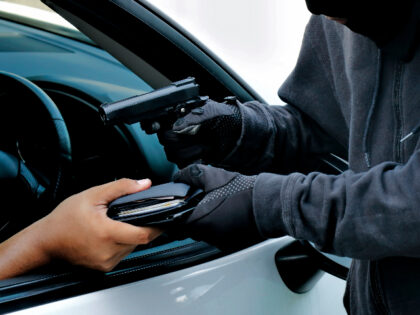Masked burglar pointing a gun at the driver
