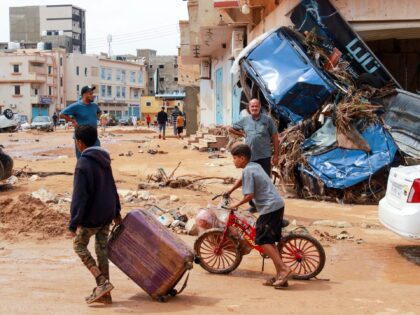 A boy pulls a suitcase past debris in a flash-flood damaged area in Derna, eastern Libya, on September 11, 2023. Flash floods in eastern Libya killed more than 2,300 people in the Mediterranean coastal city of Derna alone, the emergency services of the Tripoli-based government said on September 12. (-/AFP …