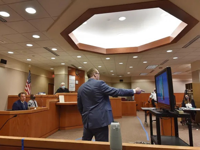 McHenry County State's Attorney Patrick Kenneally points to photographs on a flat screen as Crystal Lake Police Officer Brian Burr testifies in JoAnn Cunningham's sentencing hearing Thursday, July 16, 2020, in Woodstock, Ill. The photos were of the Cunningham home in Crystal Lake, Ill. A judge will decide if Cunningham, who pled guilty in December to killing her five-year-old son Andrew "A.J." Freund in April 2019 at her Crystal Lake home, should die in prison. (John Starks/Daily Herald via AP, Pool)