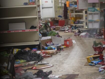 Merchandise lays strewn on the floor after looting as seen through a boarded up door of a
