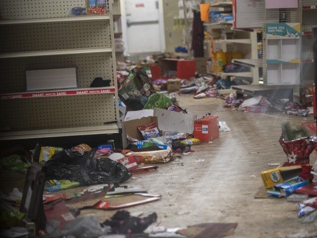 Merchandise lays strewn on the floor after looting as seen through a boarded up door of a