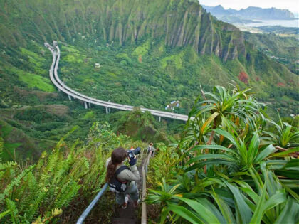 The hike up the Stairway to Heaven is also known as Haiku Stairs. It is one of the most popular trails in Oahu young woman taking photo.