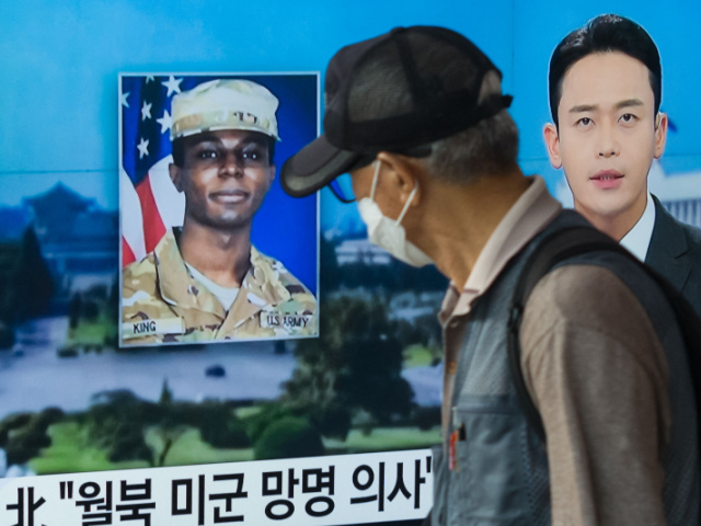 In this photo taken in Seoul on August 16, 2023, a man walks past a television showing a news broadcast featuring a photo of US soldier Travis King (C), who ran across the border into North Korea while part of a tour group visiting the Demilitarized Zone on South Korea's border on July 18. Travis King defected to North Korea to escape "mistreatment and racial discrimination in the US Army", state media said Wednesday, Pyongyang's first official confirmation they were holding the American soldier. (Photo by Anthony WALLACE / AFP) (Photo by ANTHONY WALLACE/AFP via Getty Images)