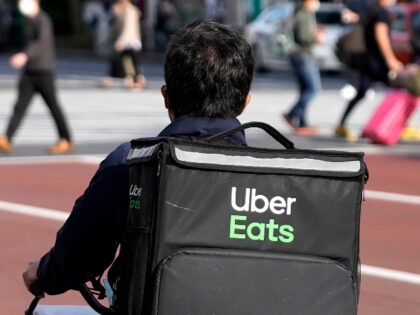 FILE - In this April 28, 2021, file photo, an Uber Eats delivery person rides a bicycle through the Shinjuku district in Tokyo, Japan. Uber’s ride-hailing service is regaining most of the momentum that it lost during the pandemic. At the same time, its delivery service is still growing at …