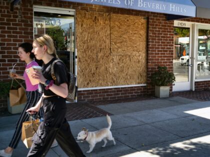 Shoppers walk past a boarded up Luxury Jewels of Beverly Hills on Wednesday, March 23, 2022 in Beverly Hills, Calif. Los Angeles police are warning people that wearing expensive jewelry in public could make them a target for thieves — a note of caution as robberies are up citywide. The …
