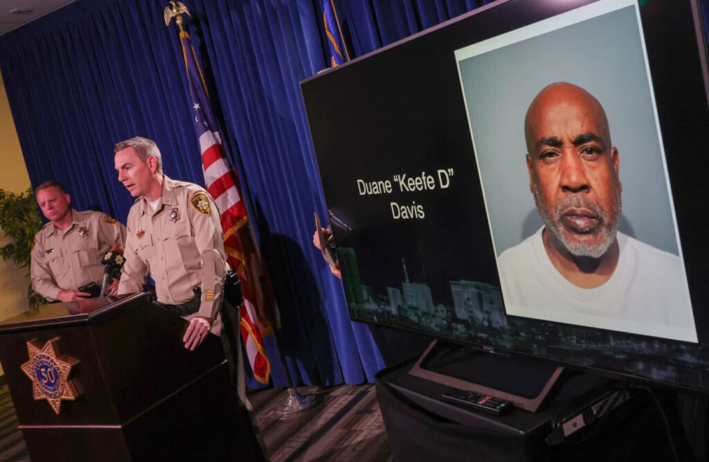 LAS VEGAS, NEVADA - SEPTEMBER 29: A booking photo of Duane "Keefe D" Davis is shown on a television monitor as Clark County Sheriff Kevin McMahill (L) and Las Vegas Metropolitan Police Department Lt. Jason Johansson speak during a news conference at the LVMPD headquarters to brief media members on Davis' arrest and indictment for the 1996 murder of Tupac Shakur on September 29, 2023 in Las Vegas, Nevada. A Nevada grand jury indicted Davis on one count of murder with a deadly weapon in the fatal drive-by shooting of rapper Tupac Shakur. (Photo by Ethan Miller/Getty Images)