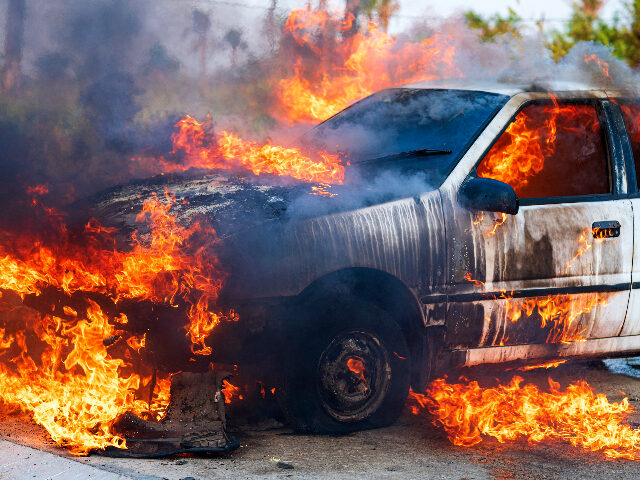 Close-up of burning car after a frontal crash collision on the roadside with flame and smo
