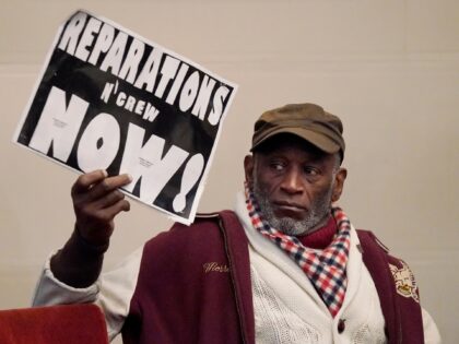 Morris Griffin holds up a sign during a meeting by the Task Force to Study and Develop Reparation Proposals for African Americans in Oakland, Calif., Wednesday, Dec. 14, 2022. (AP Photo/Jeff Chiu)