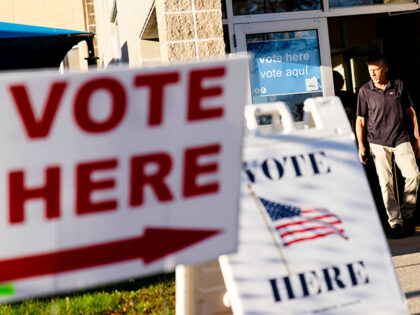 Signs point to the entrance on the last day of early voting before the midterm election as a man walks out of a polling site in Cranston, R.I., on Nov. 7, 2022. Almost half of all voters in the 2022 midterm elections cast their ballots before Election Day either by …