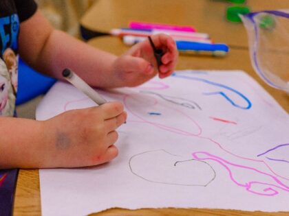 A child at a table draws a picture (Unsplash/Erika Fletcher).