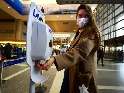 A woman wearing a facemask uses hand sanitizer on arrival at Los Angeles International Airport on March 12, 2020, one day before a US flight travel ban hits 26 European countries amid ongoing precautions over the Coronavirus. - US President Donald Trump announced a shock 30-day ban on travel from …