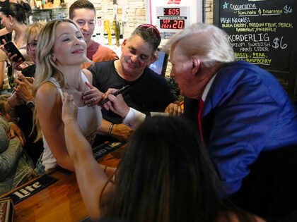 Former President Donald Trump signs an autograph for Ashley Rashid during a stop at the Treehouse Pub & Eatery, Wednesday, Sept. 20, 2023, in Bettendorf, Iowa. (AP Photo/Charlie Neibergall)