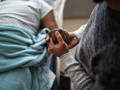 Son holding father's hand at the hospital - stock photo