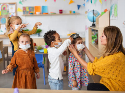 Pre school children wearing protective face masks indoors at kindergarten.