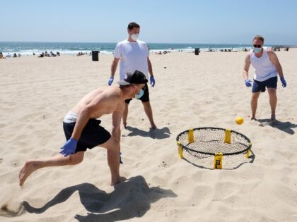 VENICE, CALIFORNIA - MAY 24: A group of men wearing protective face masks and gloves plays a game of Spikeball on Venice Beach on May 24, 2020 in Venice, California. Los Angeles County beaches and bike paths have recently reopened under the condition that face coverings be worn and that …