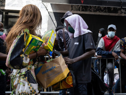 NEW YORK, NEW YORK - AUGUST 02: A woman hands out food and toiletries to migrants gathered