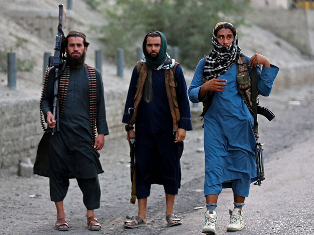 Armed Taliban security personnel pose for a photograph near the closed gates of Torkham bo