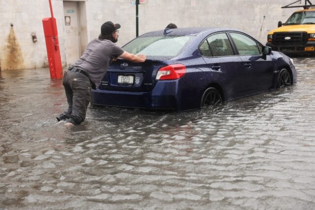 A car is pushed through flooded streets in New York's Brooklyn on September 29, 2023